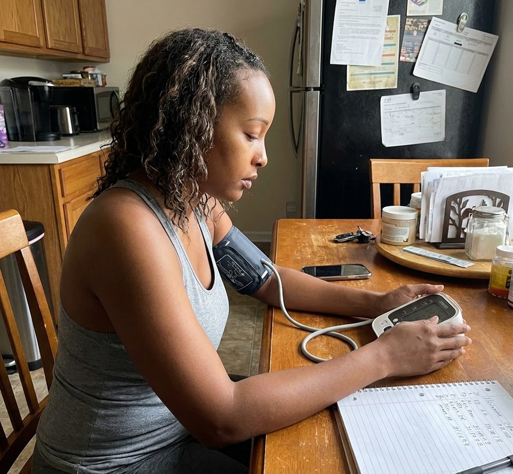 A woman taking her blood pressure at the kitchen table